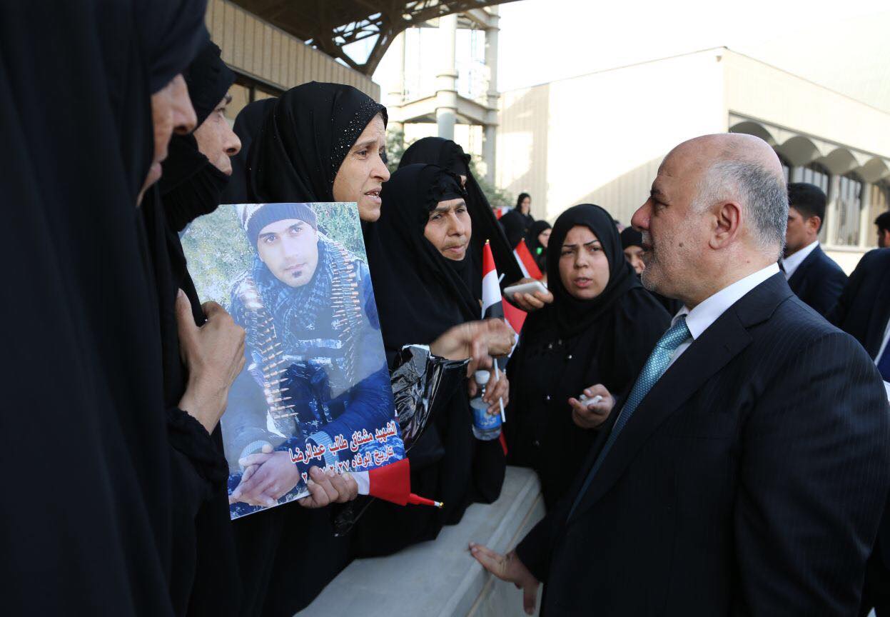 Iraqi Prime Minister Haider al-Abadi with the families of the fallen Iraqi soldiers during the military parade in Baghdad, July 15, 2017. (Photo: Iraqi Prime Minister’s Press Office)